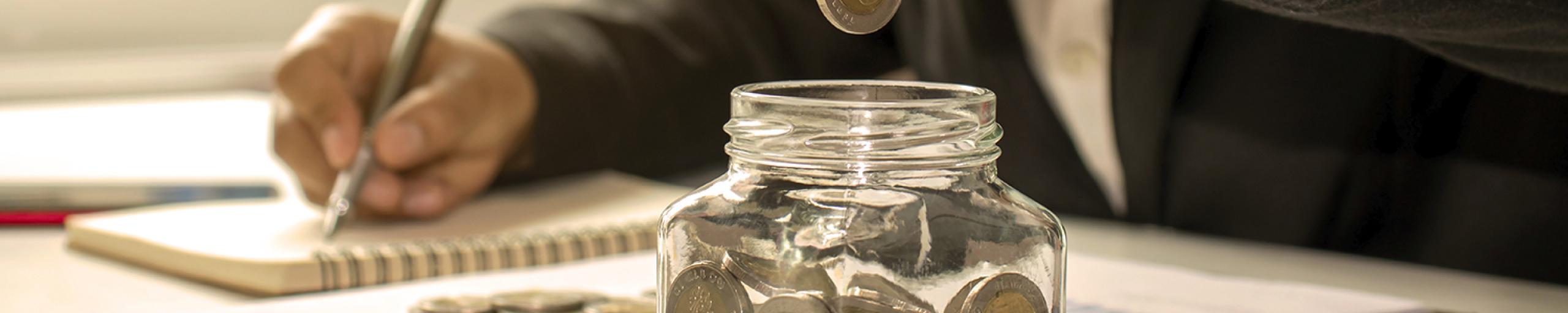 Persoon spaart geld in een pot