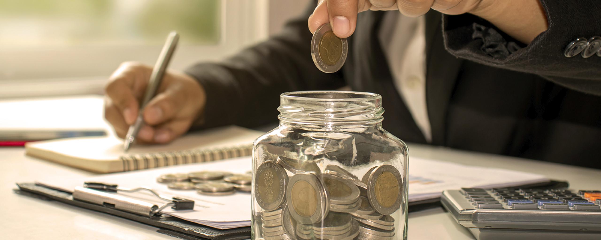 Persoon spaart geld in een pot